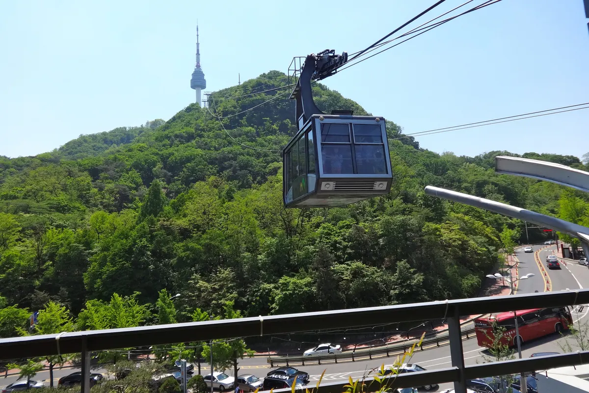 Namsan cable car gliding over the green slopes of Namsan with N Seoul Tower on the summit
