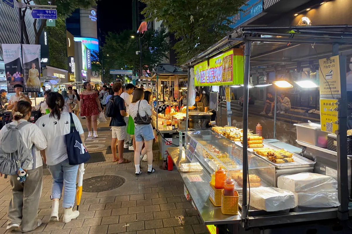 Street food stalls lit up at night on a busy Myeongdong shopping street in Seoul