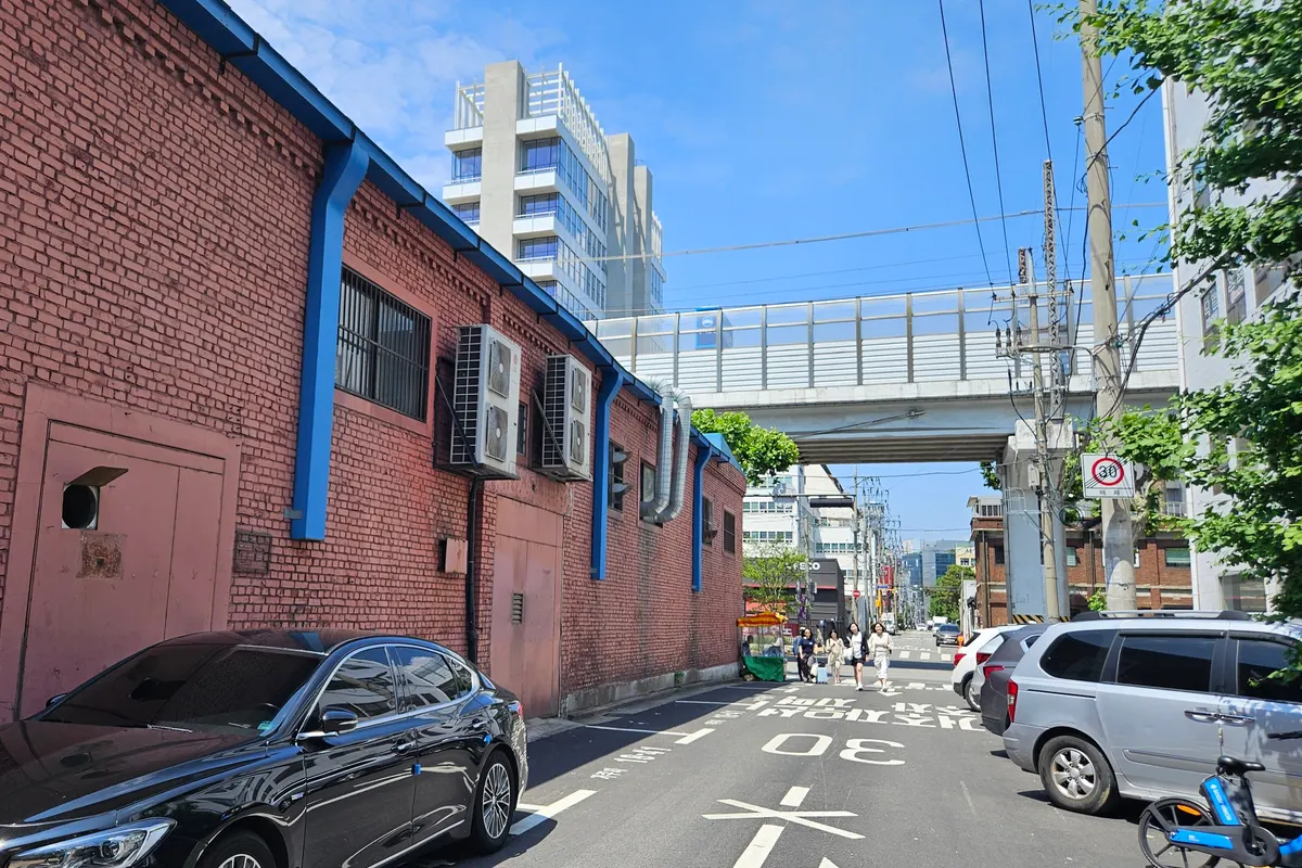Red-brick former factory building with blue drainpipes on a Seongsu-dong street in Seoul