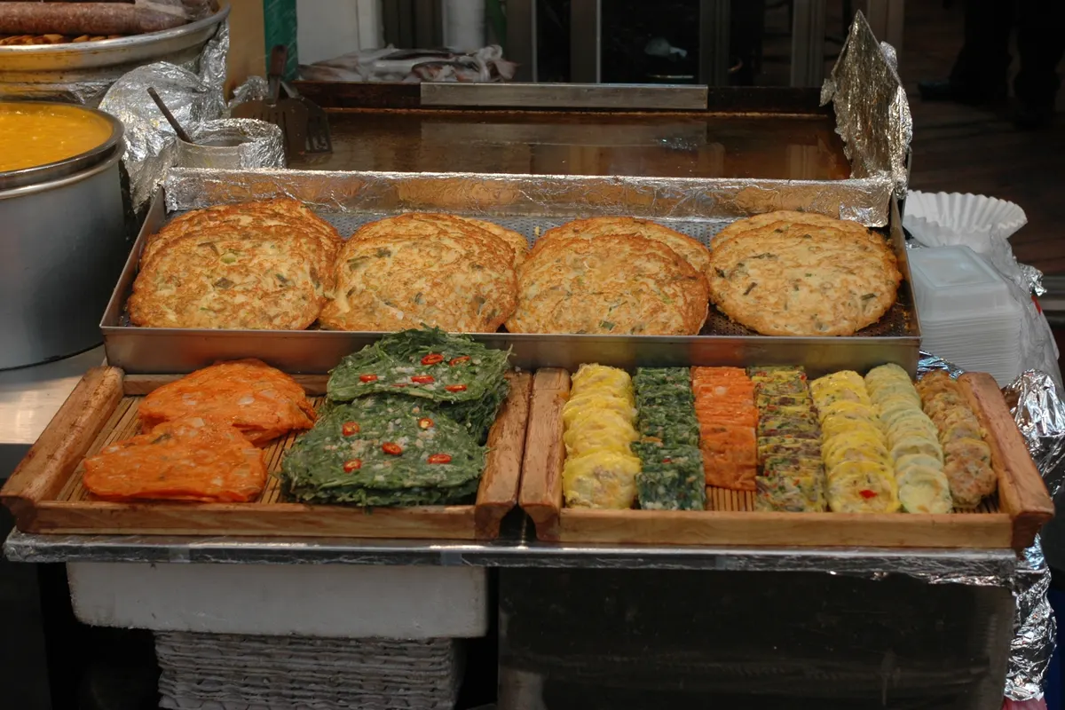 แพนเค้กถั่วเขียวและจอนทอดวางเรียงบนถาดที่ร้านอาหารในตลาดควังจัง โซล